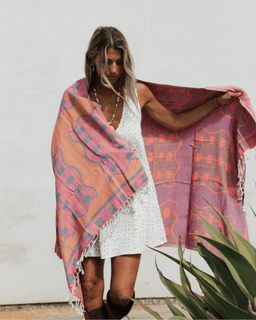 Woman holding a colorful patterned towel  in front of a white wall