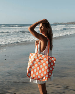 Woman on a beach holding an orange polka dot bag