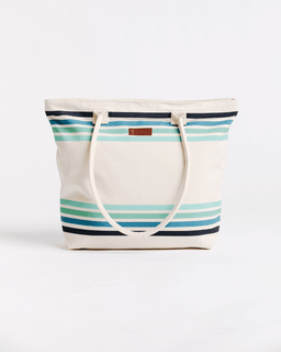 A canvas tote bag with a cream base and horizontal stripes in navy, teal, and light blue, featuring cream-colored shoulder straps and a small brown leather brand patch.