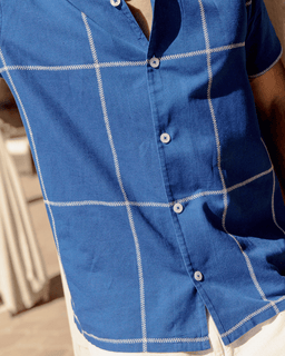 Close-up of a blue checkered shirt with white buttons and stitching.