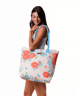 Woman holding a floral tote bag with blue handles on a white background