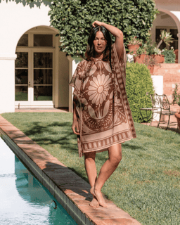 Woman in a patterned dress standing by a poolside in a garden setting