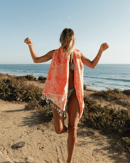 Woman on a beach with an red towel draped over her shoulders