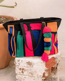 Colorful tote bag with tassels on a stone surface