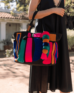 Person holding a colorful handbag with a blurred outdoor background