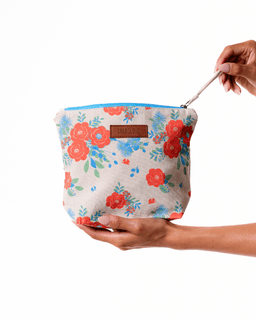 Floral-patterned pouch held by a hand on a white background