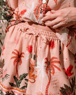 Person wearing a dress with tropical print, including palm trees and flowers.