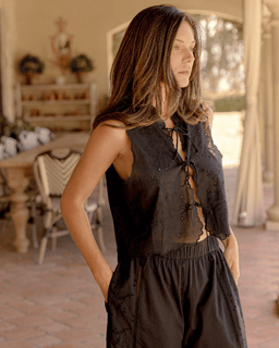 Woman wearing a black sleeveless top and pants in an outdoor setting