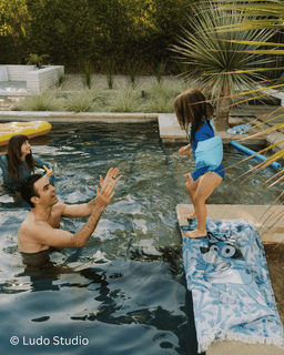 Man and child by a pool with a towel on a diving board