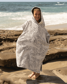Person wrapped in a patterned towel on a beach