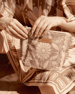 Person holding a floral-patterned clutch with 'SAND CLOUD' branding.