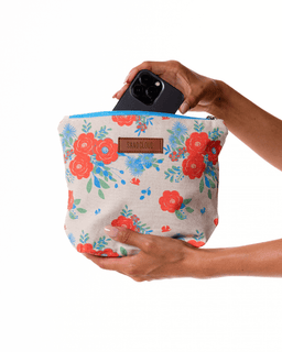 Floral-patterned pouch held by a hand with a phone inside, on a white background