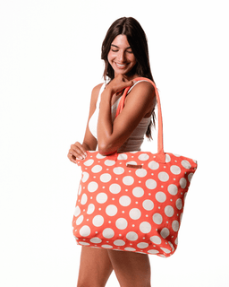 Woman holding a large pink tote bag with white polka dots on a white background