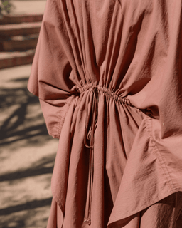 Close-up of a pinkish-brown dress with a tie waist, outdoor setting.