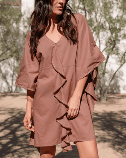 Woman wearing a brown dress with a matching jacket outdoors.
