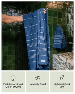 Person holding a blue striped towel in a bathroom with green tiles. Fast absorbing & quick drying, No musty smell, lightweight and soft