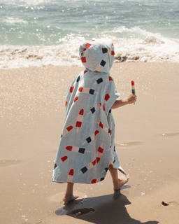 Child wearing a colorful hooded towel on a beach