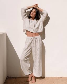 Woman wearing a white outfit against a beige wall