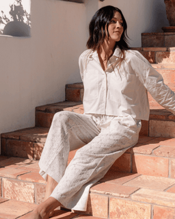 Woman in a white outfit sitting on stone steps outdoors
