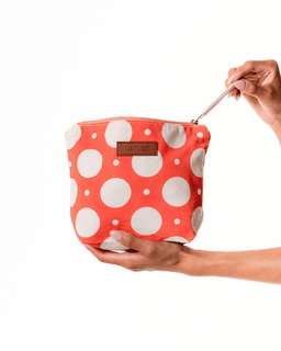 Red polka dot bag held by a hand on a white background