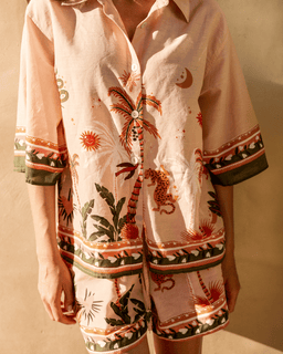 Person wearing a tropical patterned shirt and shorts against a neutral background