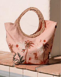 Pink tote bag with palm tree design on a wooden surface