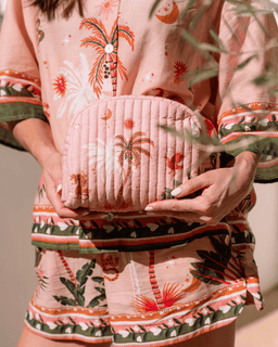 Person wearing a patterned outfit holding a pink textured bag.
