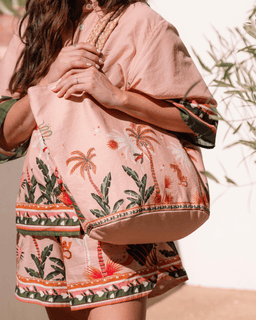 Person wearing a pink kimono with tropical patterns against a blurred natural background