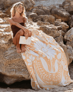 Woman sitting on rocks with a floral patterned towel draped over her