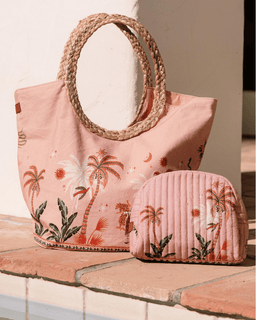 Pink tote bag with palm tree design and matching pouch on a wooden surface.