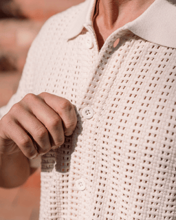 Close-up of a person wearing a textured beige cardigan with a blurred background