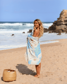 Woman standing on a beach with a blue and white patterned towel wrapped around her