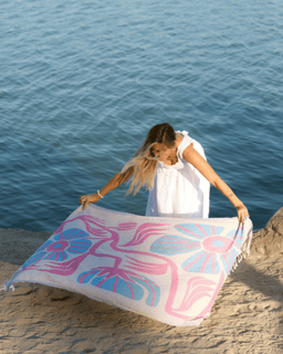 Woman holding a colorful towel by the water