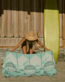 Person holding a beach towel with turtle design on a sandy background
