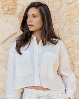 Woman wearing a light-colored shirt against a stone wall