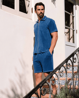Man wearing a blue outfit standing on a staircase outside a building.