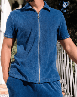 Person wearing a blue zip-up shirt with a blurred background