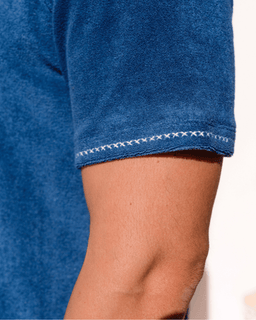 Close-up of a blue garment with white stitching detail on a neutral background