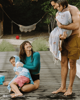 Family of four on a wooden deck with a hammock in the background