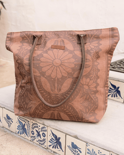 Brown tote bag with floral patterns on a decorative surface