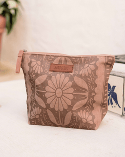 Floral-patterned pouch with a brand label on a light surface