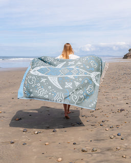 Person holding a large blue and white patterned towel on a beach