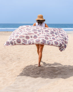 Person holding a large patterned towel on a beach