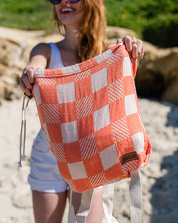 Person holding a checkered bag on a beach