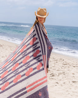 Woman on a beach wearing a patterned towel and straw hat