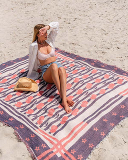 Woman sitting on a patterned beach towel on a sandy beach