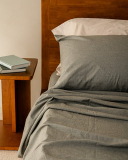 Moss bedding on a bed with a wooden headboard and nightstand.