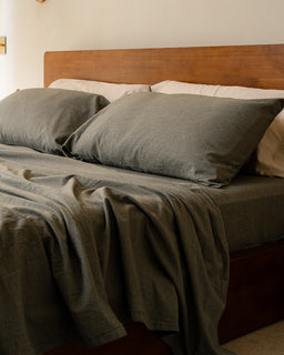Bed with green bedding and wooden headboard