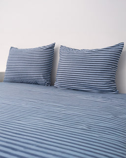 Blue and white striped bedding set on a bed with a plain background