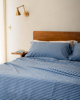 Bed with blue striped bedding in a bedroom setting.